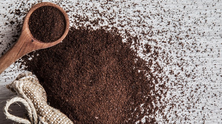 Gemahlener Kaffee liegt auf hellen Holzuntergrund, daneben ein Jutesack und ein Holzlöffel mit Kaffeepulver.