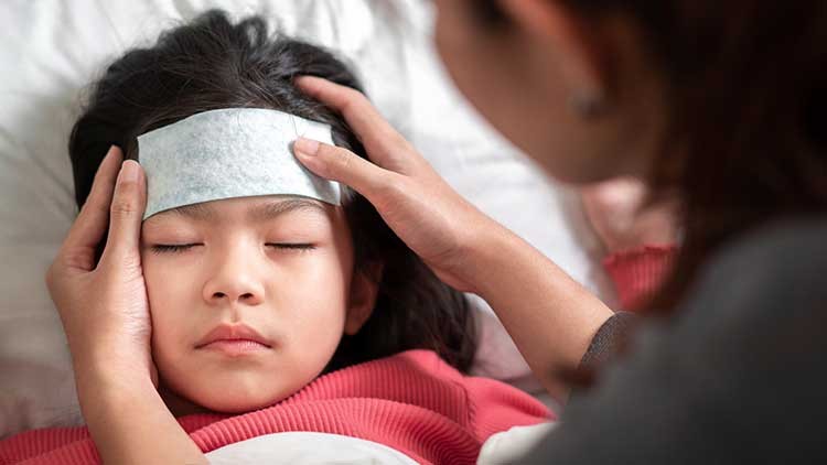 Bei einem kranken Kind wird die Stirn mit einer Kompresse gekühlt