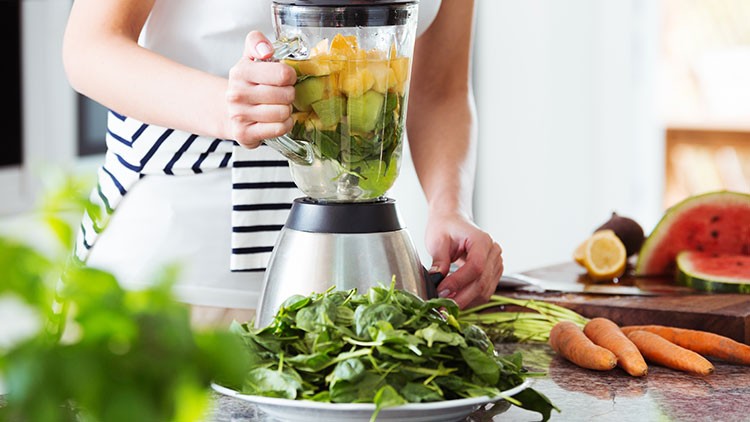 Frau bereitet mit Mixer einen Shake zu