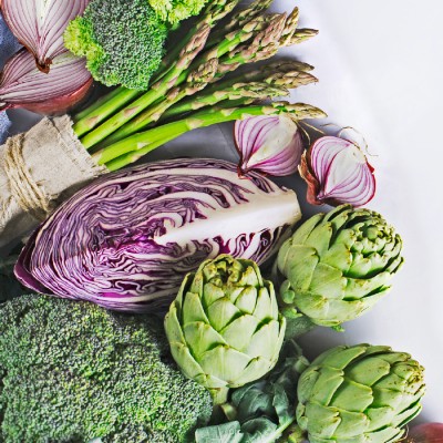 Frisches Gemüse wie Brokkoli, Artischocken, Rotkohl, rote Zwiebeln und grüner Spargel auf weißem Hintergrund.